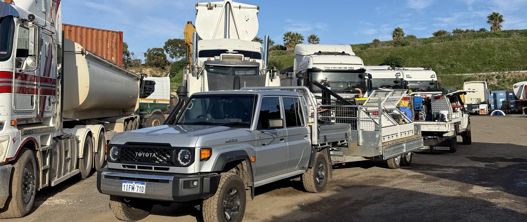 Precision Boilermaking ute and trailer parked among trucks in a yard